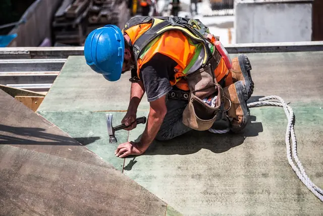 Roofing contractor working on a roof deck with a hammer